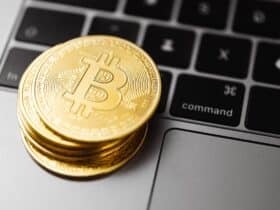 Close-up of gold bitcoin coins on a laptop keyboard, symbolizing digital currency and technology.