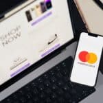 Laptop and smartphone with Mastercard logo, illustrating online shopping and digital payments.