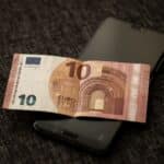 Smartphone met betaalscherm naast eurobiljetten, symbool voor de digitale euro