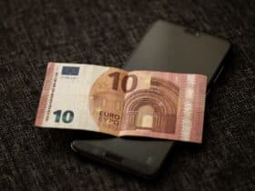 Smartphone met betaalscherm naast eurobiljetten, symbool voor de digitale euro