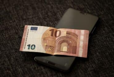 Smartphone met betaalscherm naast eurobiljetten, symbool voor de digitale euro