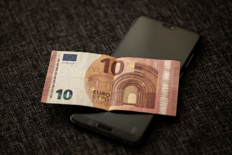 Smartphone met betaalscherm naast eurobiljetten, symbool voor de digitale euro