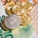 Close-up of digital cryptocurrency coins and Euro banknotes, representing modern finance.