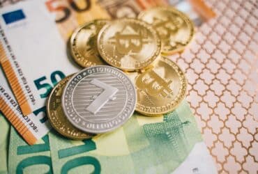 Close-up of digital cryptocurrency coins and Euro banknotes, representing modern finance.