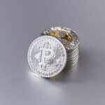 Close-up of shiny Bitcoin cryptocurrency coins with a reflective surface on a gray background.