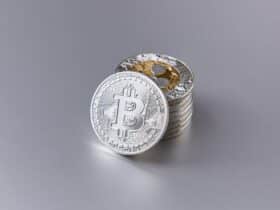 Close-up of shiny Bitcoin cryptocurrency coins with a reflective surface on a gray background.